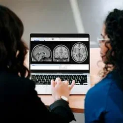 Two physicians reviewing images on a laptop screen