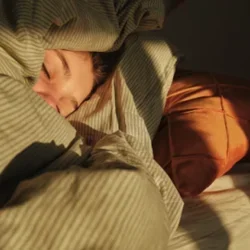 A person laying in bed with their covers up